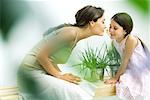 Woman and daughter smelling flower sprig together