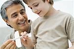 Mature man and boy holding toy plane together