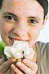 Young woman holding white flowers up to face