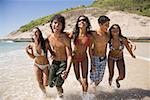 Teenagers running along a beach