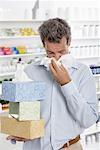 Man in Pharmacy Blowing Nose, Carrying Boxes of Tissue