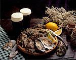 High angle view of a platter of oysters with glasses of beer on a table