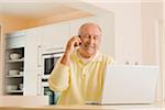 Man Talking on Cell Phone, Using Laptop Computer