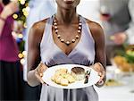 Gros plan de femme tenant la plaque de la nourriture à la fête de Noël