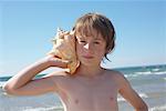 Boy Holding Seashell to His Ear, Elmvale, Ontario, Canada