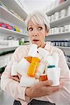 Woman in Pharmacy with Armful of Medicine
