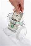 Close-up of a person's hand picking a US dollar bill from a jar