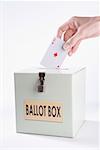 Person's hand inserting a playing card into a ballot box