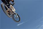 Low angle view of a young man jumping with his bicycle