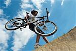 Low angle view of a young man carrying a mountain bike