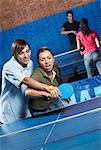 Young man teaching table tennis to a young woman