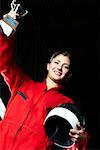 Portrait of a female go-cart racer holding a trophy with her hand raised and smiling