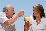 Senior couple toasting with glasses of juice and smiling