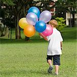 Rückansicht eines jungen mit Ballons in einem park