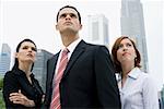 Close-up of a businessman standing with two businesswomen