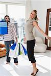 Young woman smiling with a young man holding shopping bags beside her