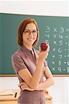 Portrait of a female teacher holding an apple and smiling