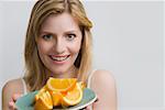 Portrait of a teenage girl holding a plate of oranges and smiling