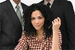 Portrait of a businesswoman holding a pen with two businessmen behind her