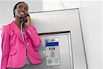 Businesswoman talking on a pay phone at an airport