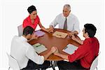 Three businessmen and a businesswoman praying with holding their hands in a meeting