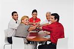 Three businessmen and two businesswomen stacking hands on top of each other in a meeting