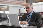 Kaufmann mit einem Laptop auf einem Flughafen