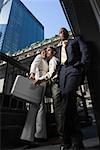 Low angle view of two businessmen and a businesswoman standing together