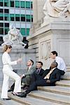 Side profile of four businessmen and a businesswoman discussing on steps