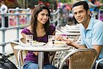 Portrait d'un homme adult moyen propose à une jeune femme dans un café de trottoir