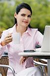 Portrait of a businesswoman sitting on a chair and holding a cup of coffee