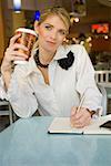 Businesswoman writing in a diary and smiling in a restaurant