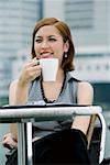 Close-up of a businesswoman drinking coffee at a sidewalk cafe