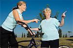 Two senior women standing with bicycles and pointing