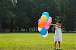 Girl holding balloons in a park