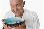 Close-up of a senior man holding a bowl and smiling