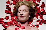 Erhöhte Ansicht einer reifen Frau liegend auf einem Massagetisch mit Rosenblüten um sie herum