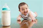 Close-up of a baby boy smiling near a baby bottle