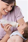 Close-up of a mid adult woman feeding her son with a baby bottle