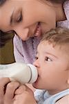Gros plan d'une femme adulte mid nourrir son fils avec une bouteille de bébé