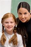 Portrait of a female teacher smiling with a schoolgirl in a classroom