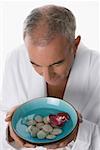 High angle view of a senior man holding a bowl of water with pebbles and floating flower