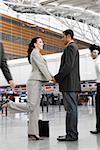 Businessman and a businesswoman standing at an airport with holding each other's hands
