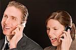 Businessman with a businesswoman talking on mobile phones