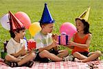 Three children sitting together on a picnic blanket