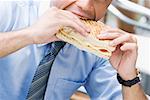 Close-up of a businessman eating a cheese sandwich