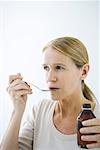 Mature woman taking a spoonful of medicine