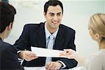 Meeting between professional and clients, man passing document to woman