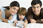 Little boy playing video game, parents watching