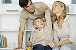 Little boy playing with toy airplane, parents watching